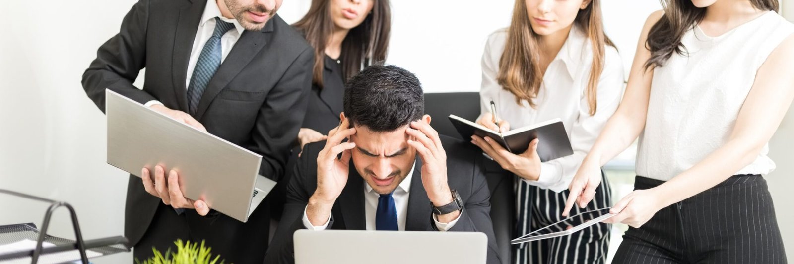 Stressed businessman unable to cope with too much work assigned by colleagues in office